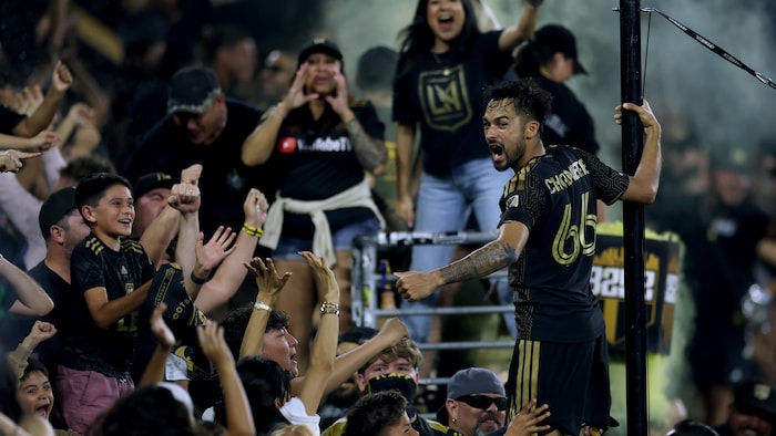 Un joueur de soccer célèbre avec des partisans.