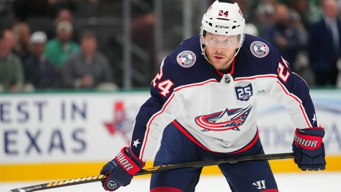 Un hockeyeur est penché sur son bâton.