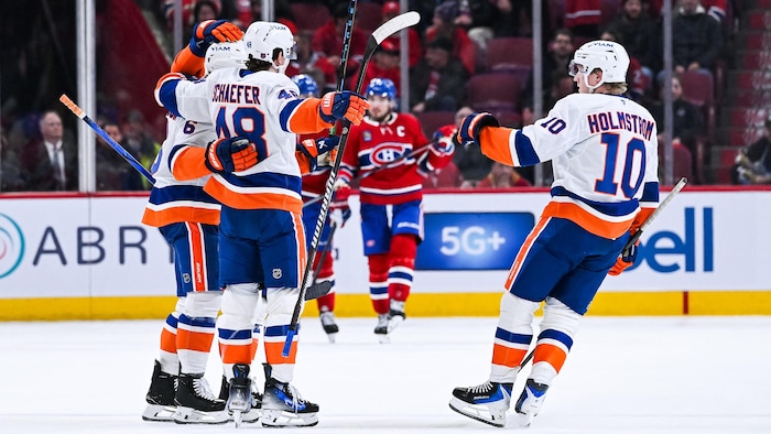 Des joueurs célèbrent un but près d'un adversaire.