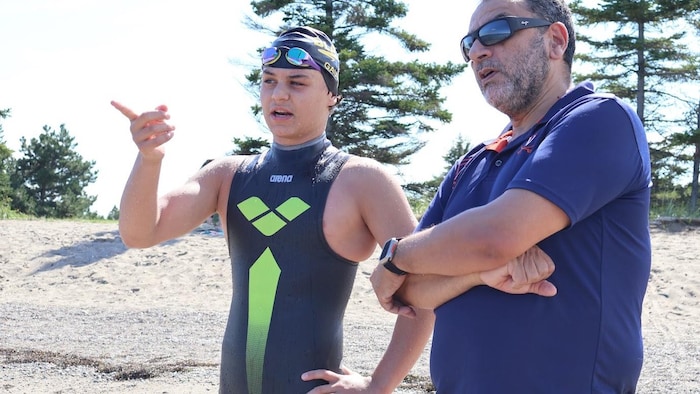 Un nageur et un homme discutent sur une plage.