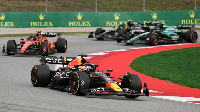 Max Verstappen, dans sa voiture Red Bull, devance une Ferrari, une Mercedes et une Aston Martin dans les premiers virages de la course. 