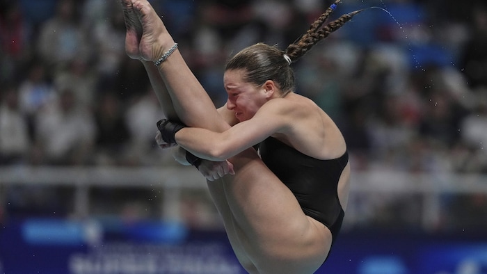 Elle effectue un plongeon en position carpée.