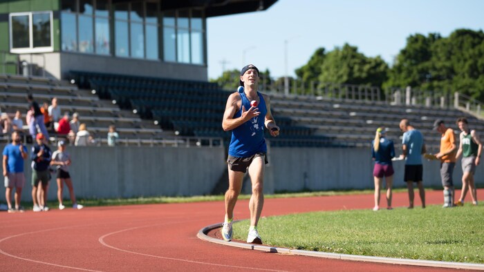 Un homme court sur une piste d'athlétisme en jonglant avec trois balles.