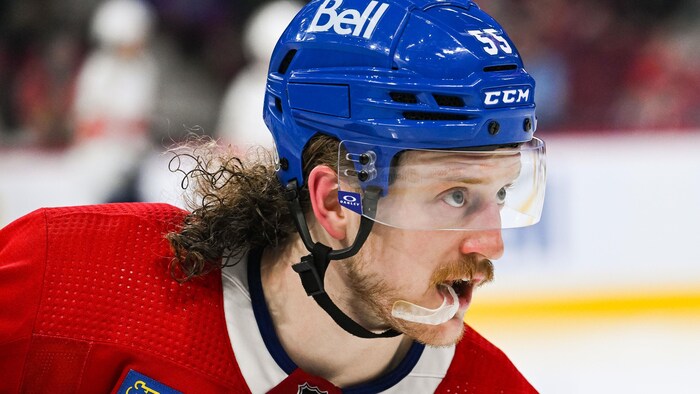 Le hockeyeur aux cheveux longs mordille son protecteur buccal.