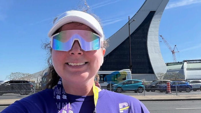 Une coureuse sourit pendant qu'elle se trouve devant la tour du Stade olympique.
