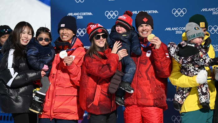 Médaille d'or au cou, il prend une photo avec ses proches.