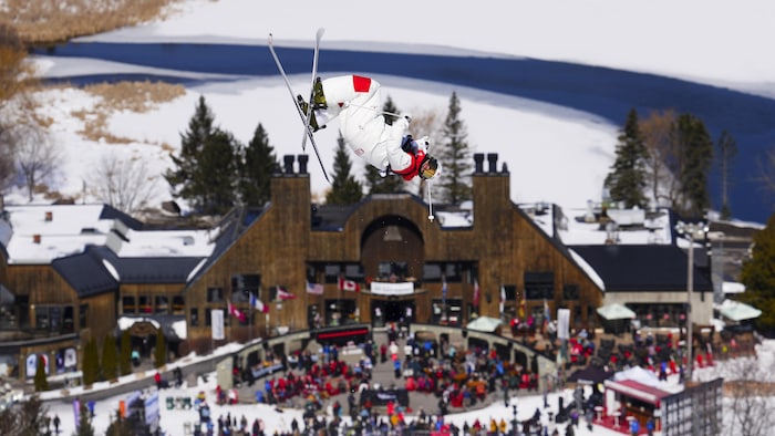 Un skieur acrobatique effectue un saut devant le chalet du Sommet Saint-Sauveur. 