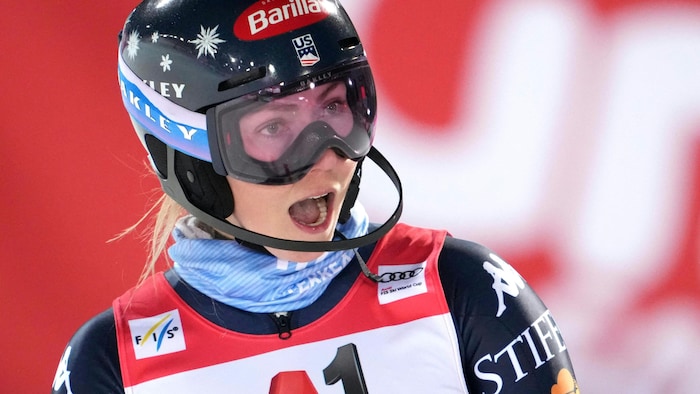 Une skieuse croise le fil d'arrivée bouche bée.