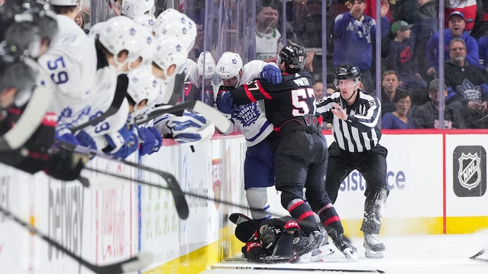 Deux hockeyeurs se bousculent sur la patinoire.