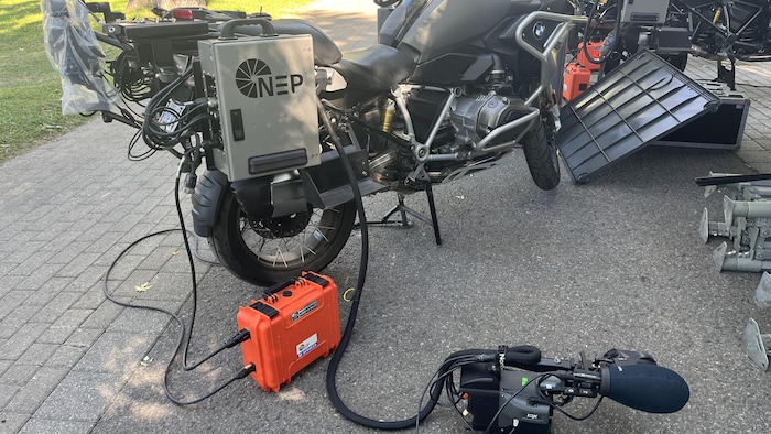 Une caméra a été déposée au sol à côté d'une moto.