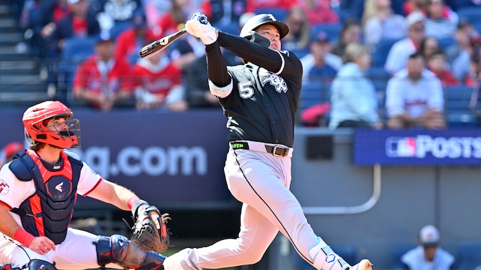 Un joueur de baseball termine son élan devant un receveur. 