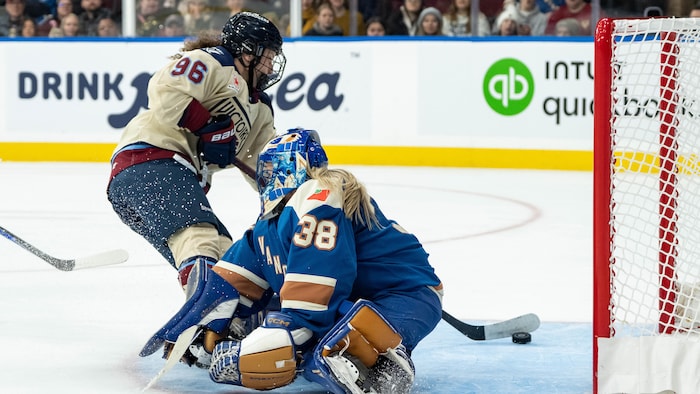 Une joueuse de hockey déjoue une gardienne.