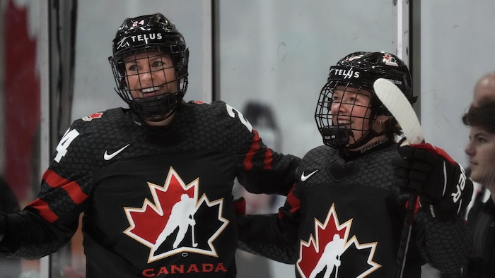 Deux joueuses de hockey sourient après avoir inscrit un but.