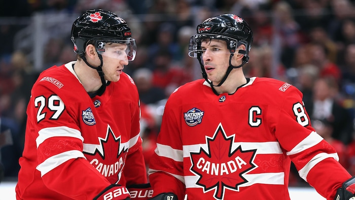 Deux hockeyeurs discutent pendant un arrêt de jeu.