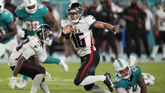 Un footballeur évite un plaqué d'un adversaire qui plonge.