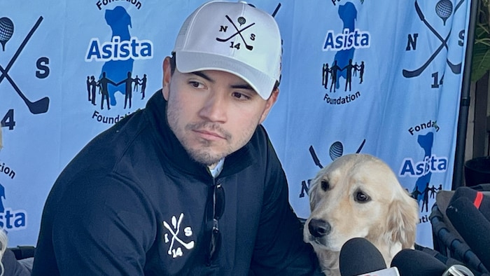 Un homme et son chien regardent quelqu'un parler.