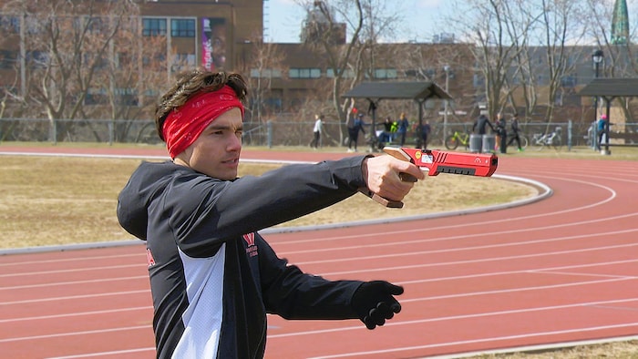 Un jeune homme vise une cible avec un pistolet au laser.