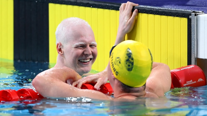 Il sourit dans la piscine en faisant face à son adversaire.