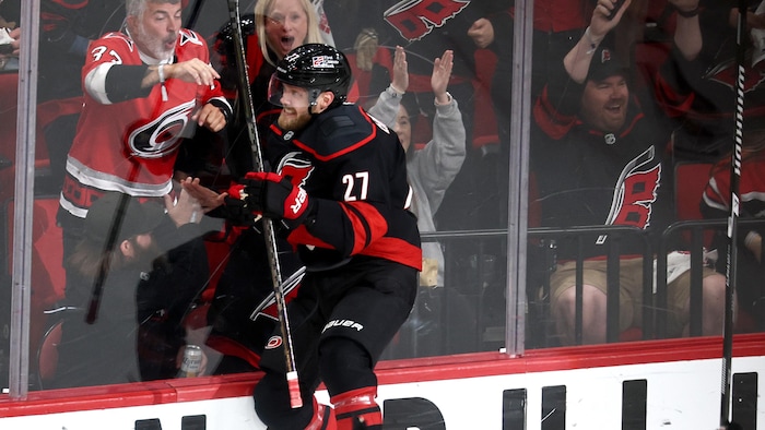Un hockeyeur en maillot noir saute dans la bande pour célébrer son but. 