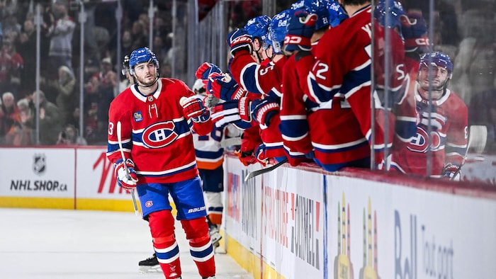 Un joueur de hockey est félicité par ses coéquipiers au banc.