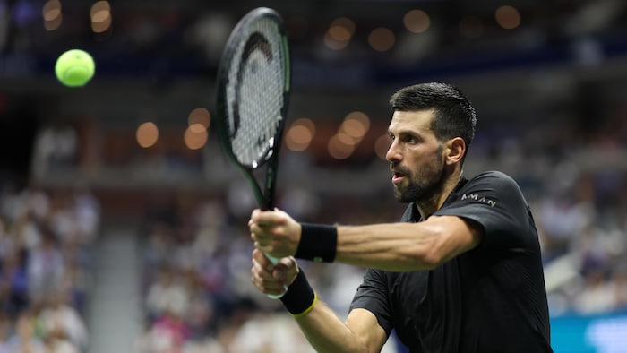 Un joueur de tennis frappe un revers.