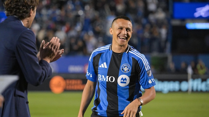 Un homme applaudit un autre homme qui sourit.