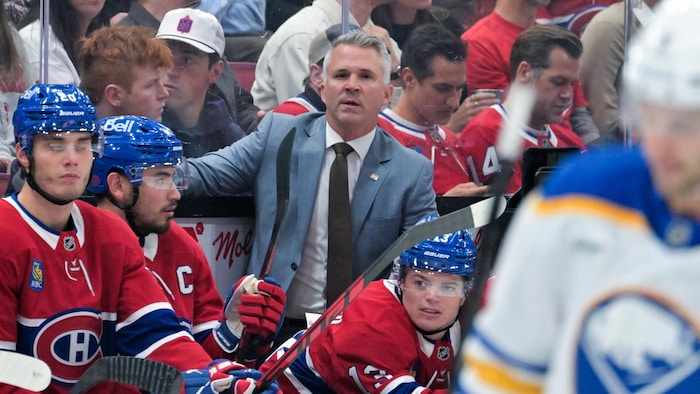 Un entraineur de hockey regarde l'action depuis le banc.