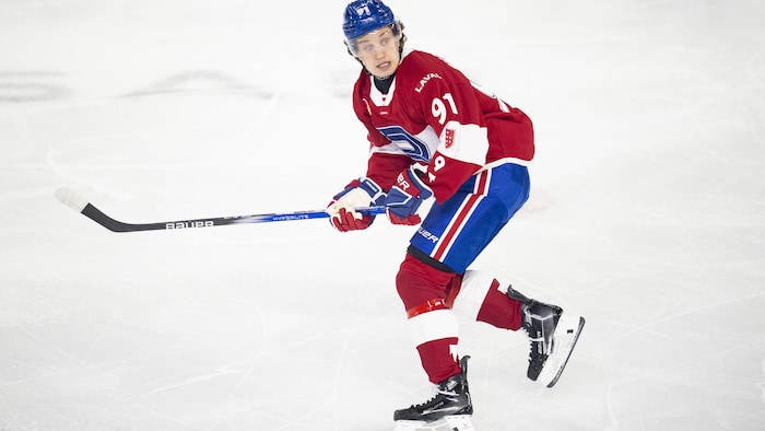 Un joueur de hockey patine en regardant derrière lui.