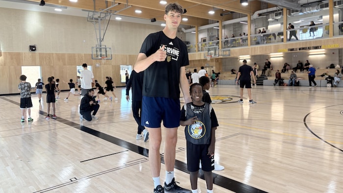 Un homme prend une photo avec un enfant, qui ne fait pas la moitié de sa taille.