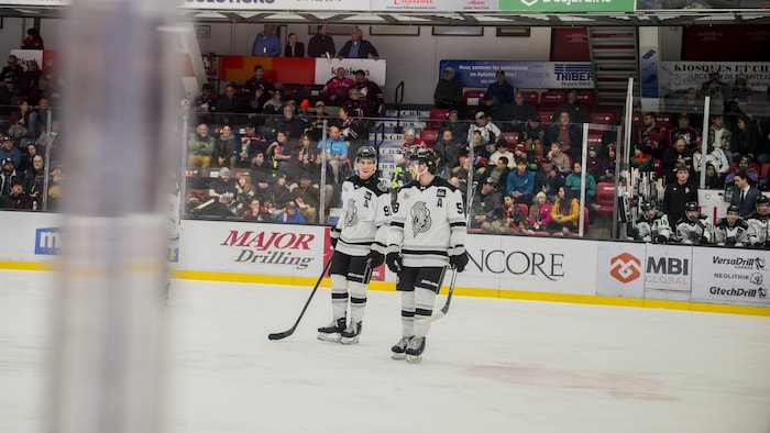 Deux joueurs de hockey junior se parlent pendant un arrêt de jeu.