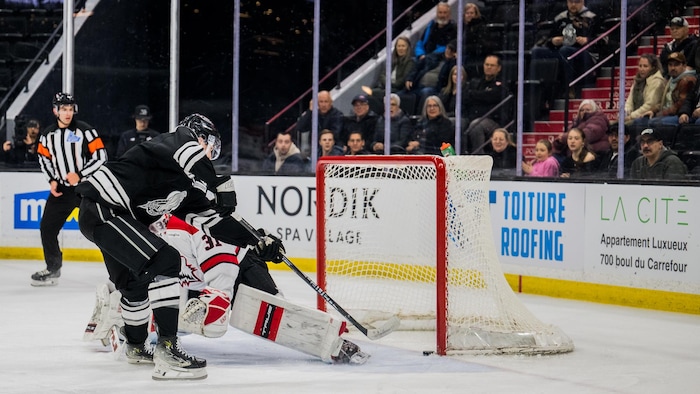 Un joueur de hockey déjoue un gardien pendant un match junior.