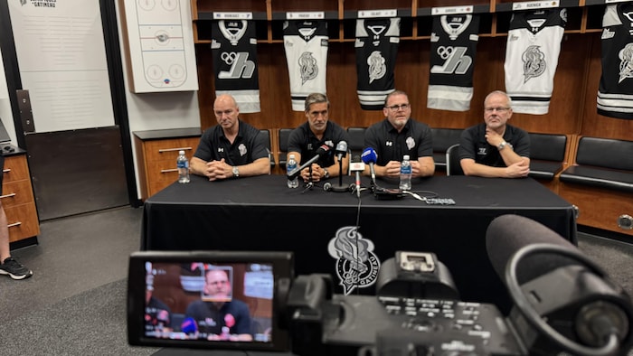 Les dirigeants d'une équipe de hockey donnent une conférence de presse.