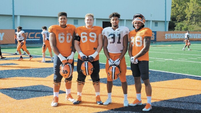 Quatre joueurs de shot   en orangish  prennent une photograph  ensemble après un entraînement. 