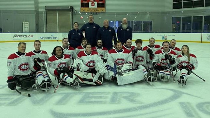 Des parahockeyeurs posent sur la glace.