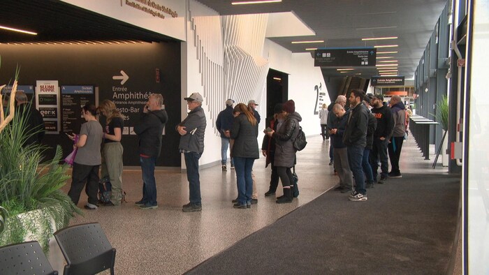 Des partisans de hockey font la file devant une billetterie.