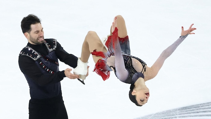 Un couple de patineurs artistiques effectuent une figure sur la glace.