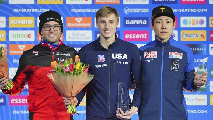 Trois patineurs de vitesse posent sur le podium.