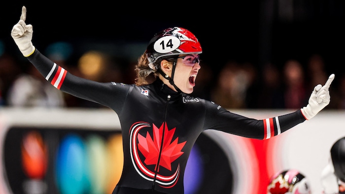 Une patineuse lève ses bras pour célébrer une victoire.