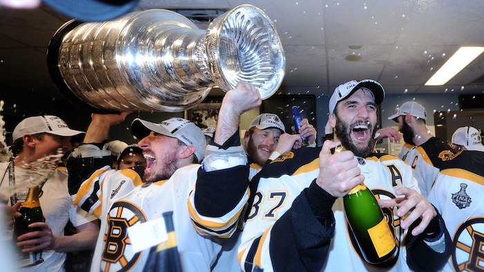 Des joueurs de hockey célèbrent leur conquête dans le vestiaire en s'arrosant de champagne.