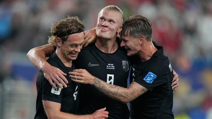 Trois joueurs de soccer célèbrent un but.
