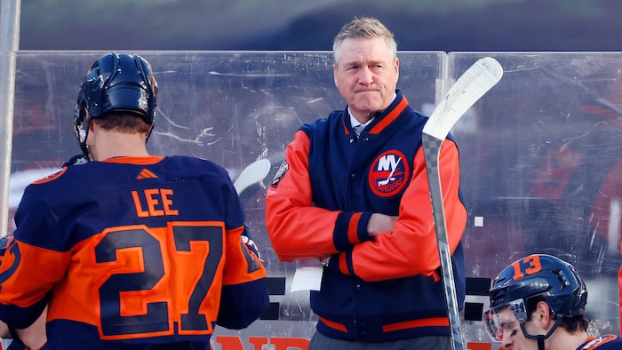 A head coach with his arms noah dobson, little story smoking crossed behind the players' bench.