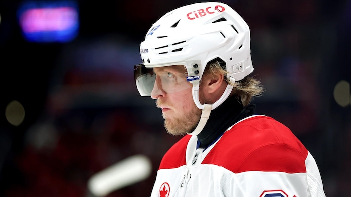Un hockeyeur en blanc a un air concentré sur la glace.