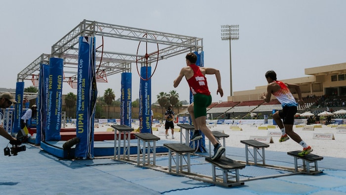Deux athlètes courent sur des obstacles.