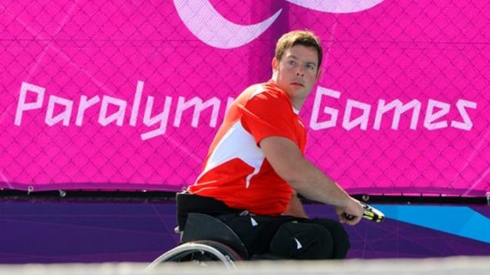 Philippe Bédard en fauteuil roulant retourne une balle de tennis.