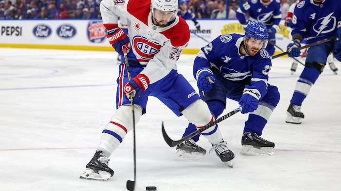 Un hockeyeur tente un lancer du revers lorsqu'il est contré par un adversaire.