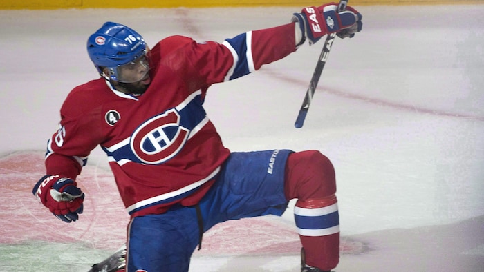Un joueur de hockey pose un genou sur la glace pour célébrer un but.