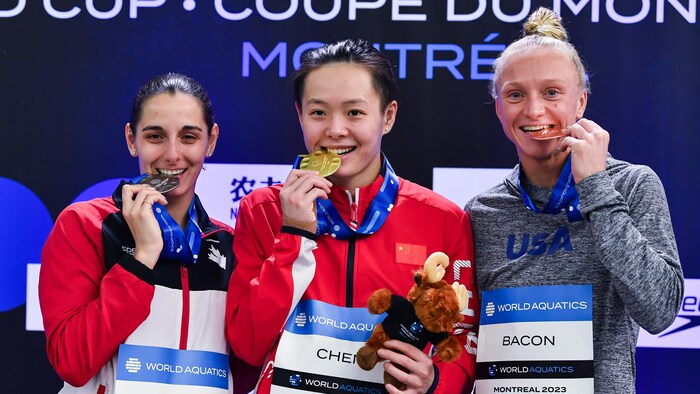 Trois plongeuses croquent leur médaille sur le podium.