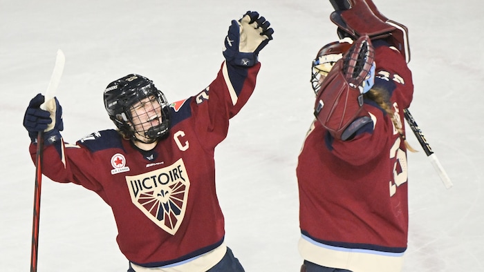Deux joueuses de hockey lèvent les bras. 