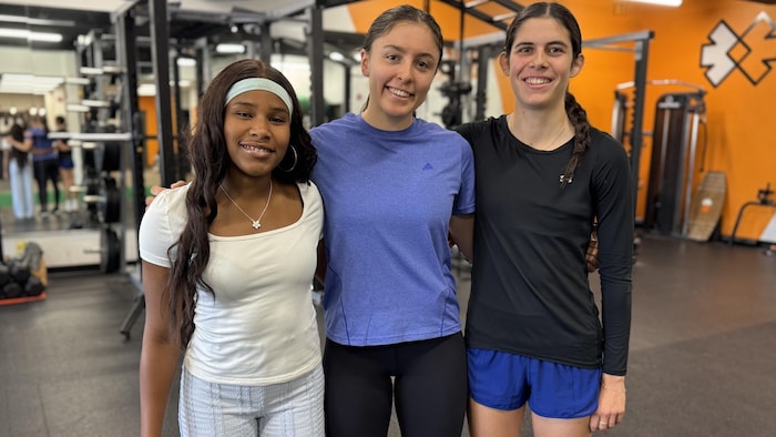 Trois jeunes athlètes prennent la airs determination un photographe dans un gymnase.