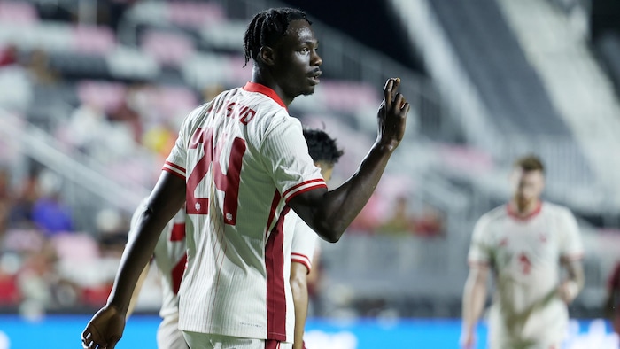Un joueur de soccer regarde au loin en croisant les doigts. 
